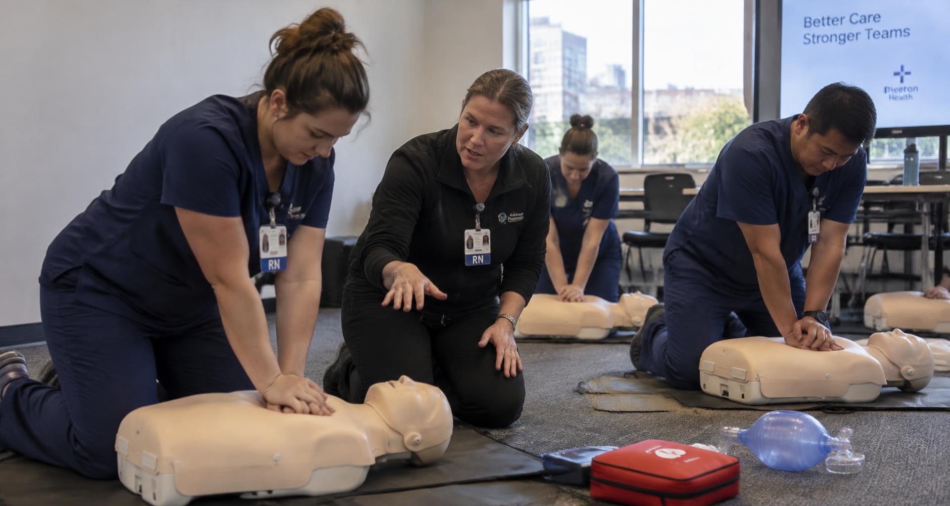 Illustrative scene of nurses practicing CPR compressions with an instructor in a hospital conference room